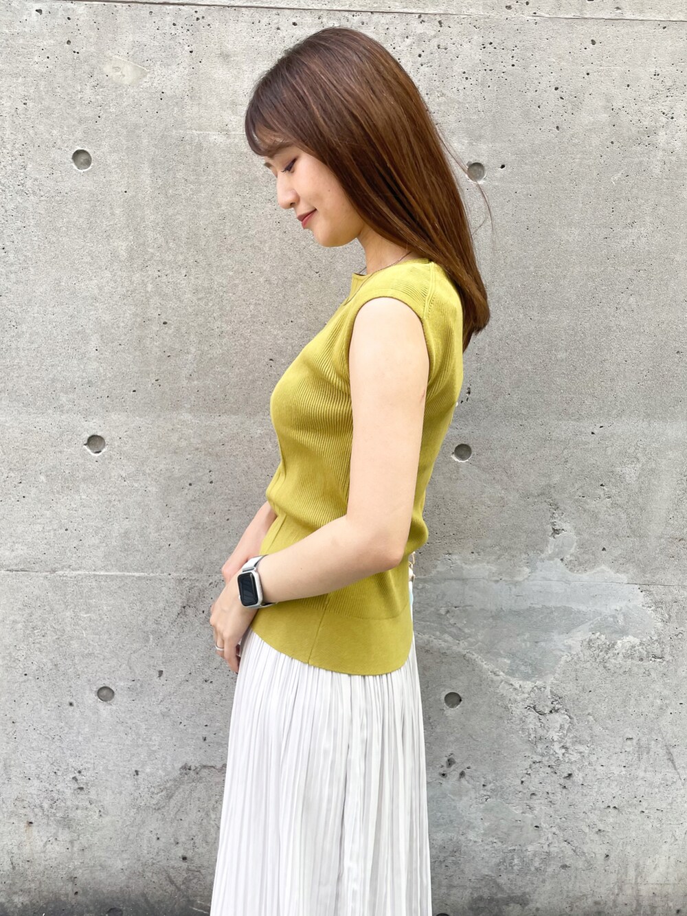 イエロー系のニット/セーター、ベージュ系のショルダーバッグ、グレー系のスカートを着用したレディースの夏コーディネートの4枚目の写真