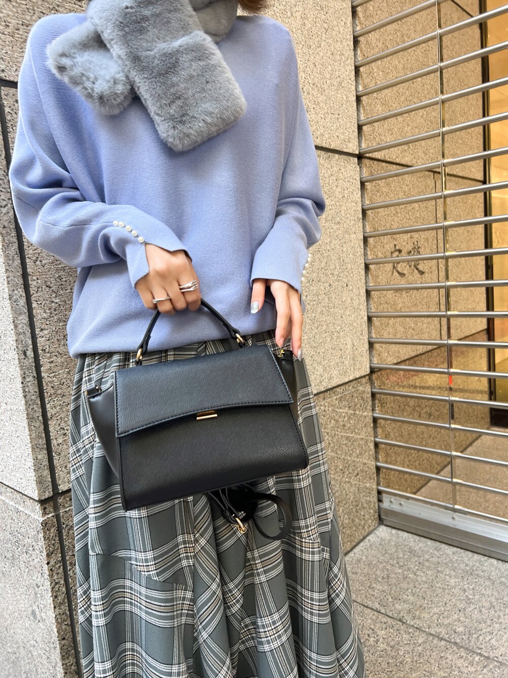 ブルー系のニット/セーター、ブラック系のショルダーバッグ、グレー系のスカートを着用したレディースの冬コーディネートの5枚目の写真