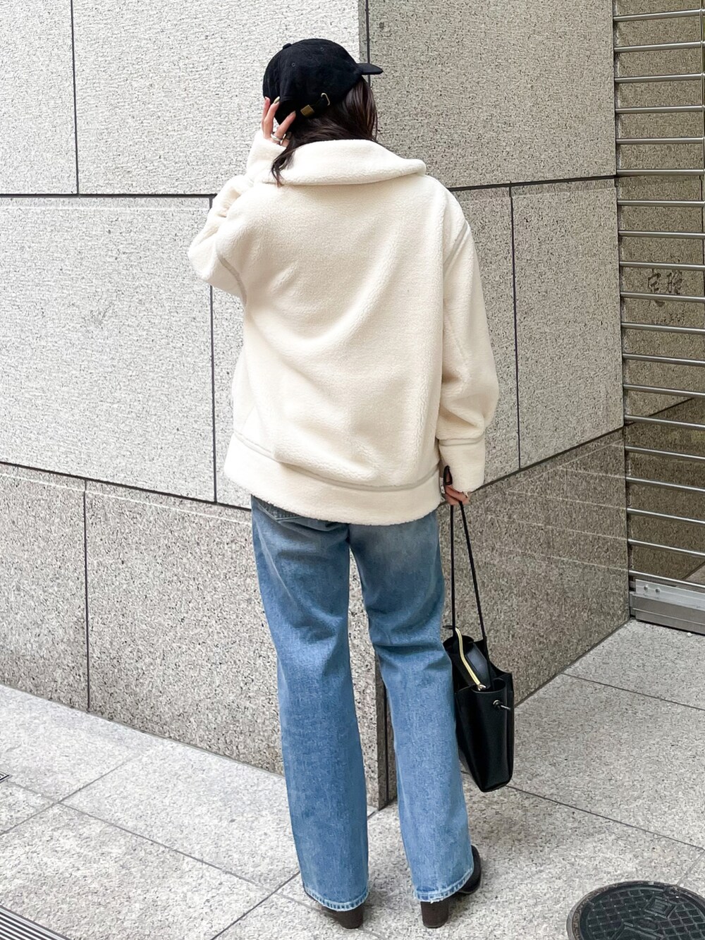 ブラック系のニット/セーター、ブラック系のブーツ、ブルー系のデニムパンツを着用したレディースの冬コーディネートの2枚目の写真