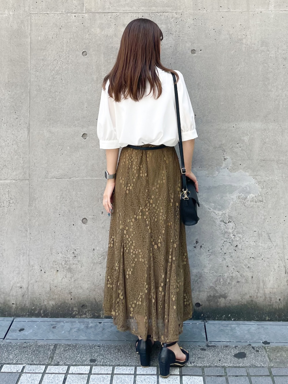 ブラック系のショルダーバッグ、グリーン系のスカート、ブラック系のサンダルを着用したレディースの夏コーディネートの2枚目の写真