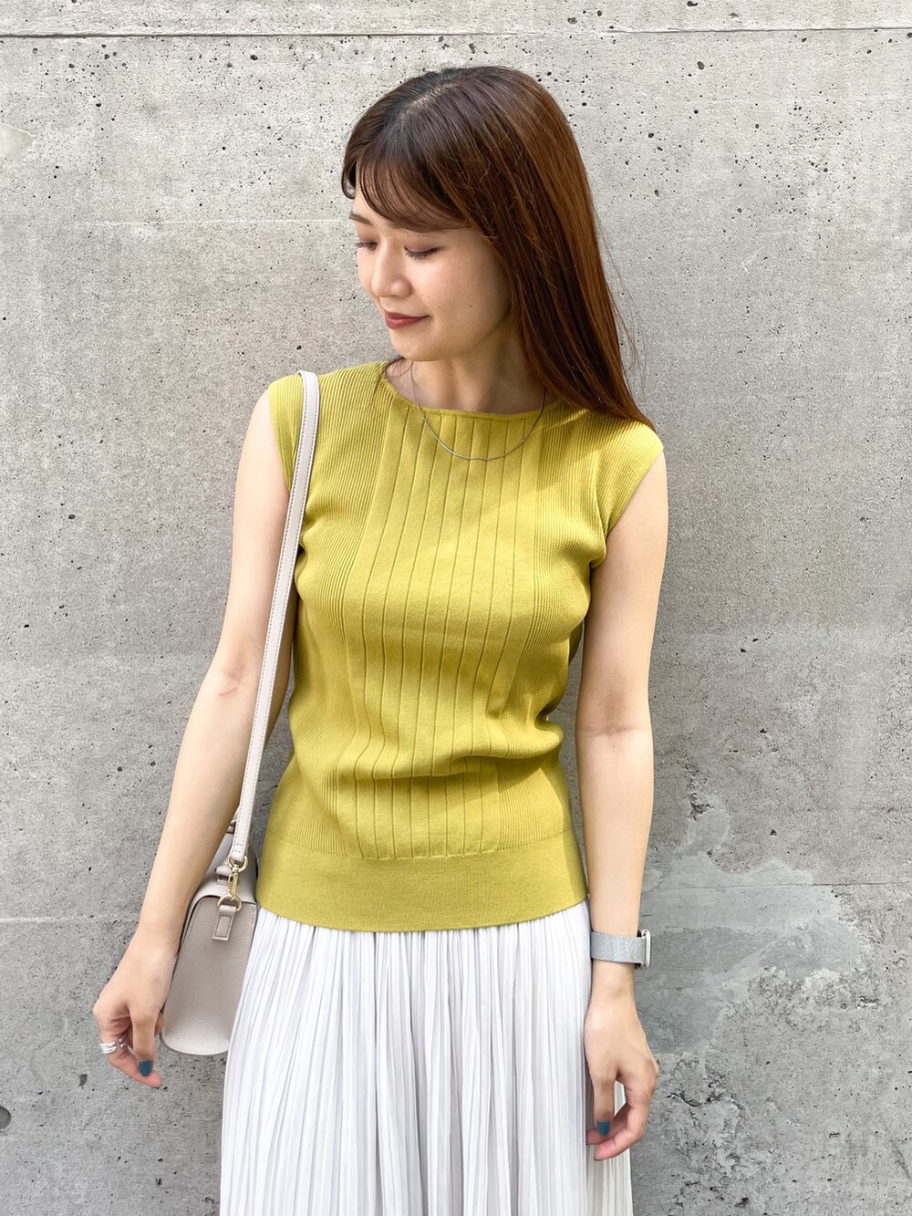 イエロー系のニット/セーター、ベージュ系のショルダーバッグ、グレー系のスカートを着用したレディースの夏コーディネートの3枚目の写真