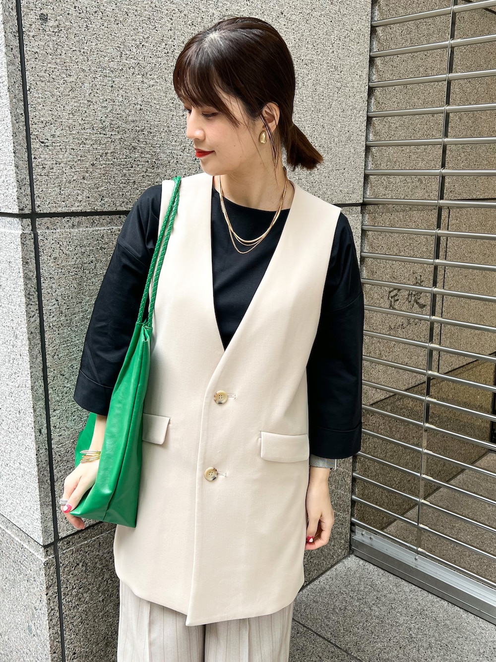 ブラック系のTシャツ/カットソー、ベージュ系のベスト、グリーン系のトートバッグを着用したレディースの春コーディネートの4枚目の写真