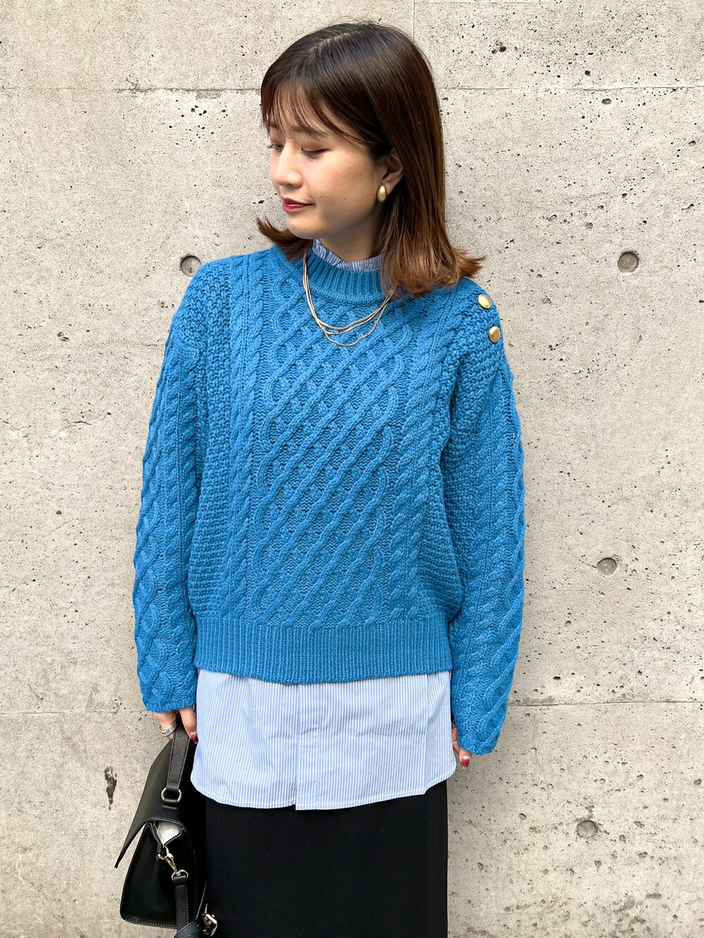 ブルー系のニット/セーター、ブルー系のシャツ/ブラウス、ブラック系のショルダーバッグを着用したレディースの冬コーディネートの3枚目の写真