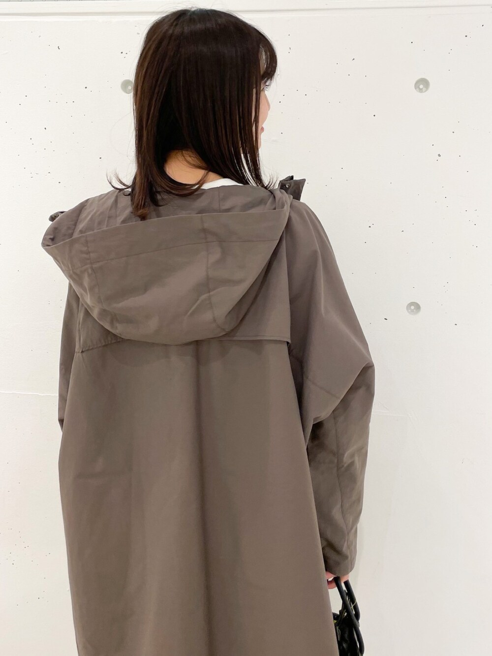 ブラウン系のマウンテンパーカー、ブラック系のショルダーバッグ、ホワイト系のワンピースを着用したレディースの冬コーディネートの4枚目の写真