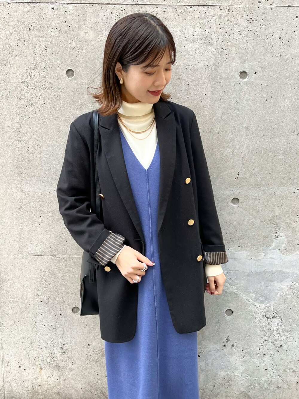 ブラック系のテーラードジャケット、ブルー系のジャンパースカート、ホワイト系のニット/セーターを着用したレディースの冬コーディネートの3枚目の写真