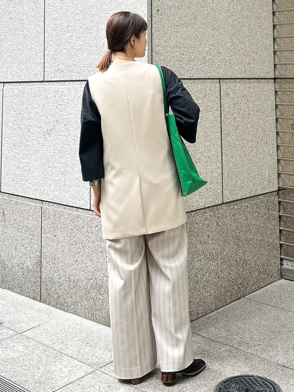 ブラック系のTシャツ/カットソー、ベージュ系のベスト、グリーン系のトートバッグを着用したレディースの春コーディネートの3枚目の写真