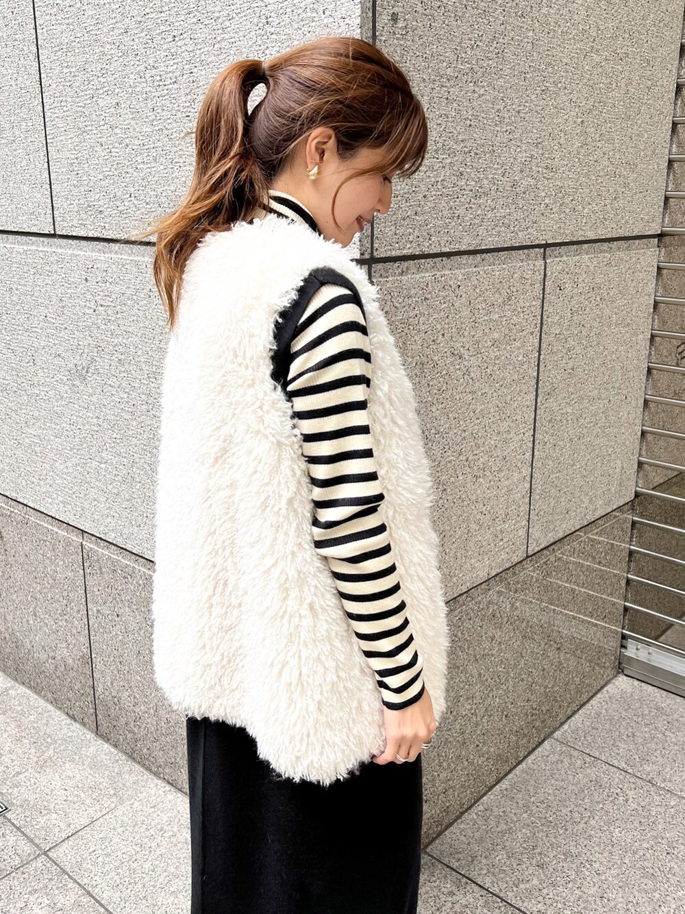 ブラック系のジャンパースカート、ホワイト系のニット/セーター、ホワイト系のベストを着用したレディースの秋コーディネートの5枚目の写真