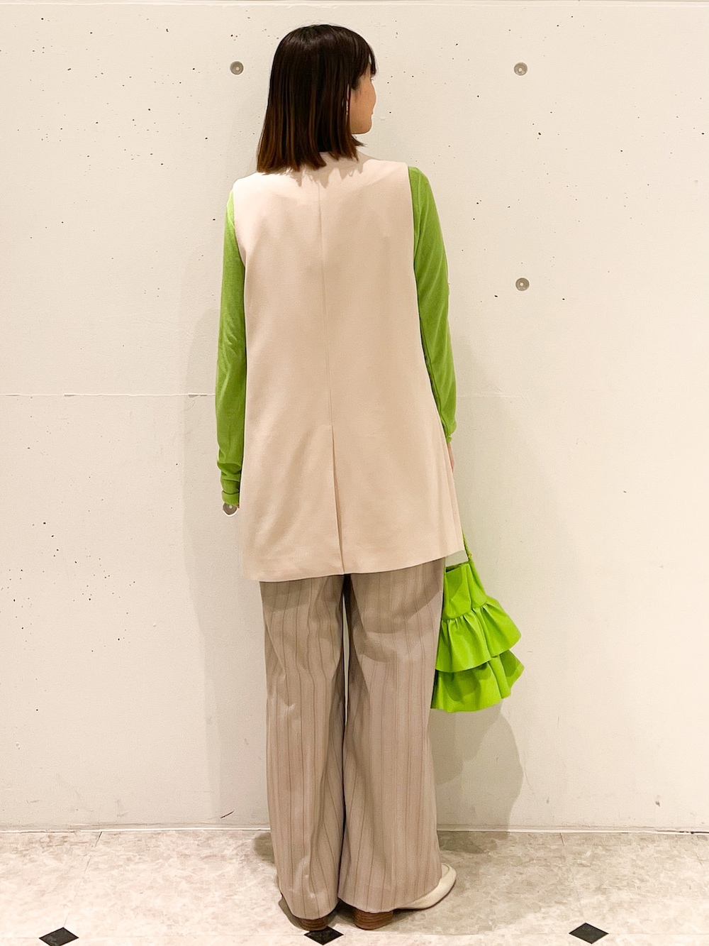 グリーン系のTシャツ/カットソー、ベージュ系のベスト、グリーン系のトートバッグを着用したレディースの春コーディネートの2枚目の写真