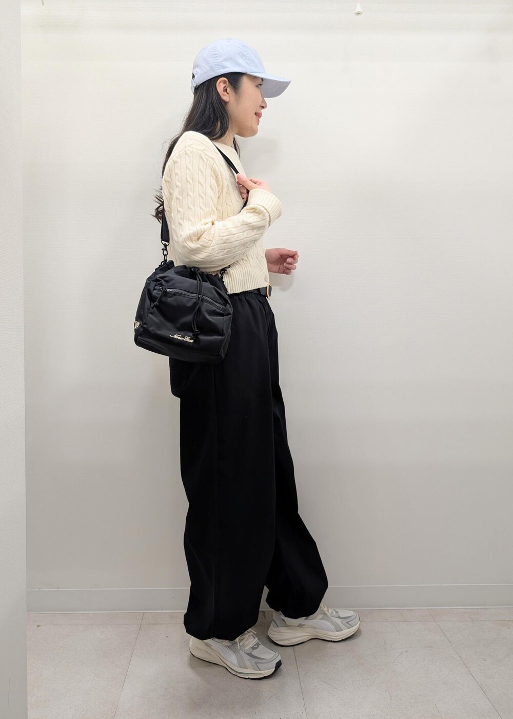 ブラック系のその他パンツ、ホワイト系のニット/セーター、グレー系のスニーカーを着用したレディースの春コーディネートの6枚目の写真