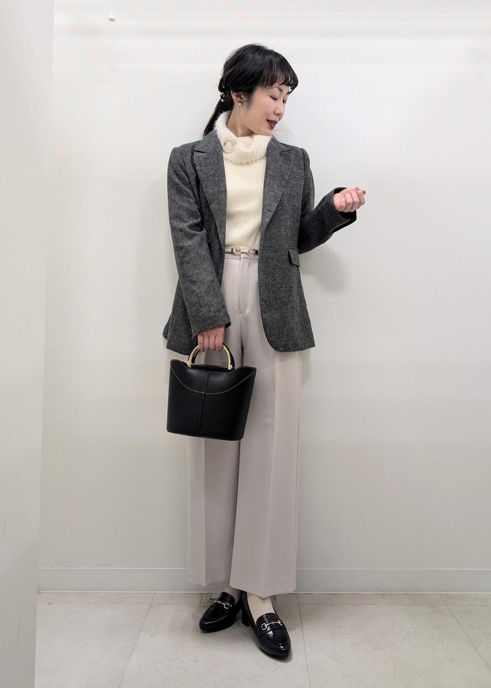 ホワイト系のニット/セーター、ブラック系のテーラードジャケット、ブラック系のショルダーバッグを着用したレディースの冬コーディネートの2枚目の写真