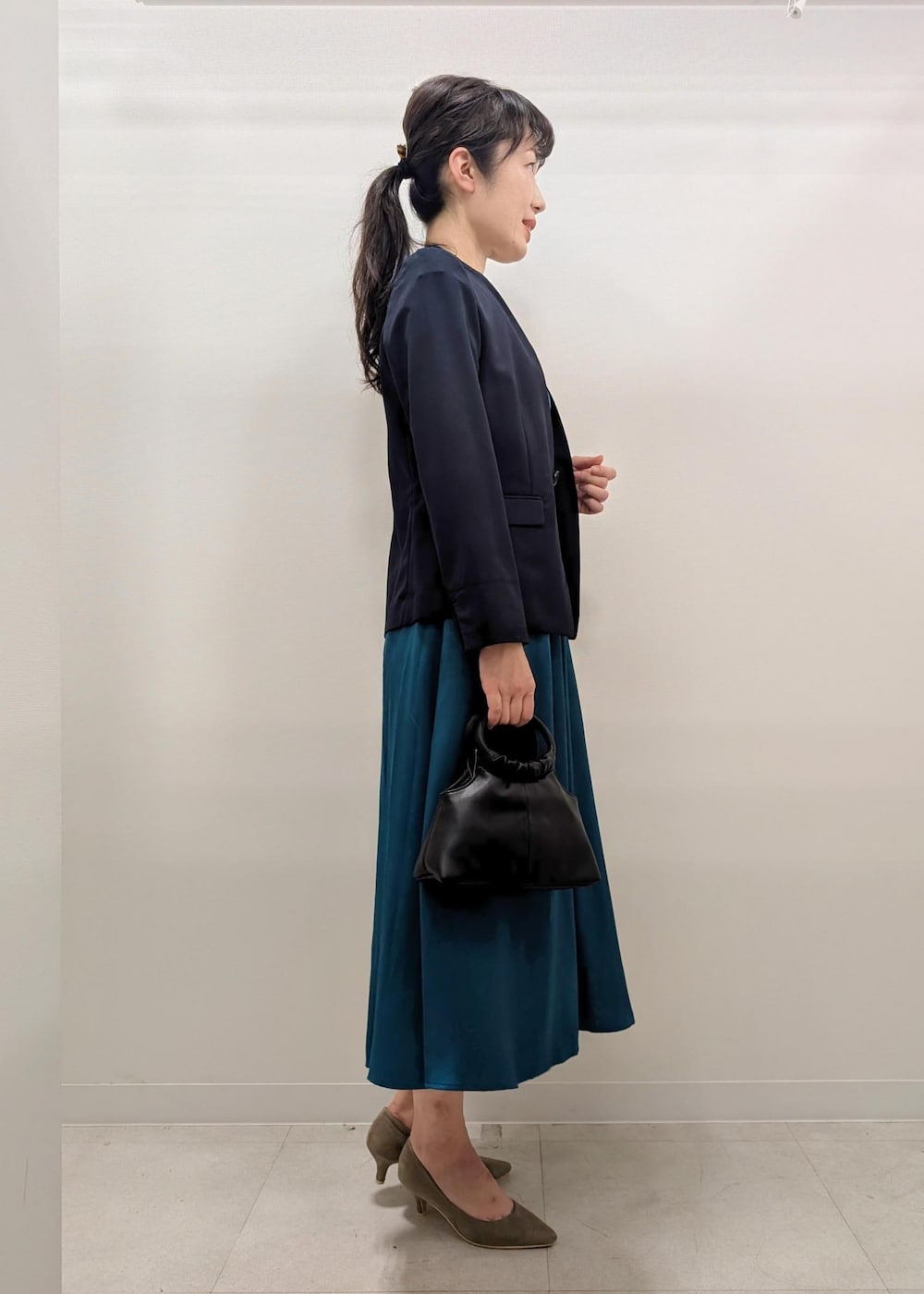 ベージュ系のパンプス、ブルー系のノーカラージャケット、ブラック系のショルダーバッグを着用したレディースの夏コーディネートの2枚目の写真