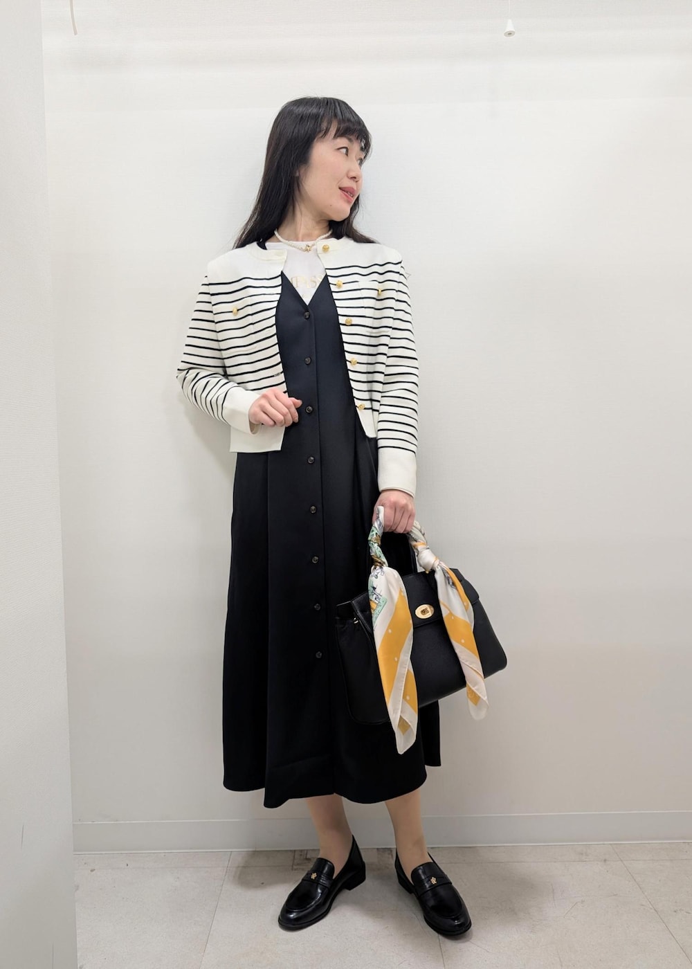 ブラック系のローファー、ブラック系のトートバッグ、ホワイト系のカーディガン/ボレロを着用したレディースの春コーディネートの2枚目の写真