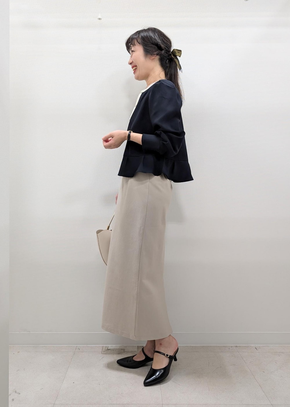 ベージュ系のスカート、ホワイト系のトートバッグ、ブラック系のパンプスを着用したレディースの秋コーディネートの3枚目の写真