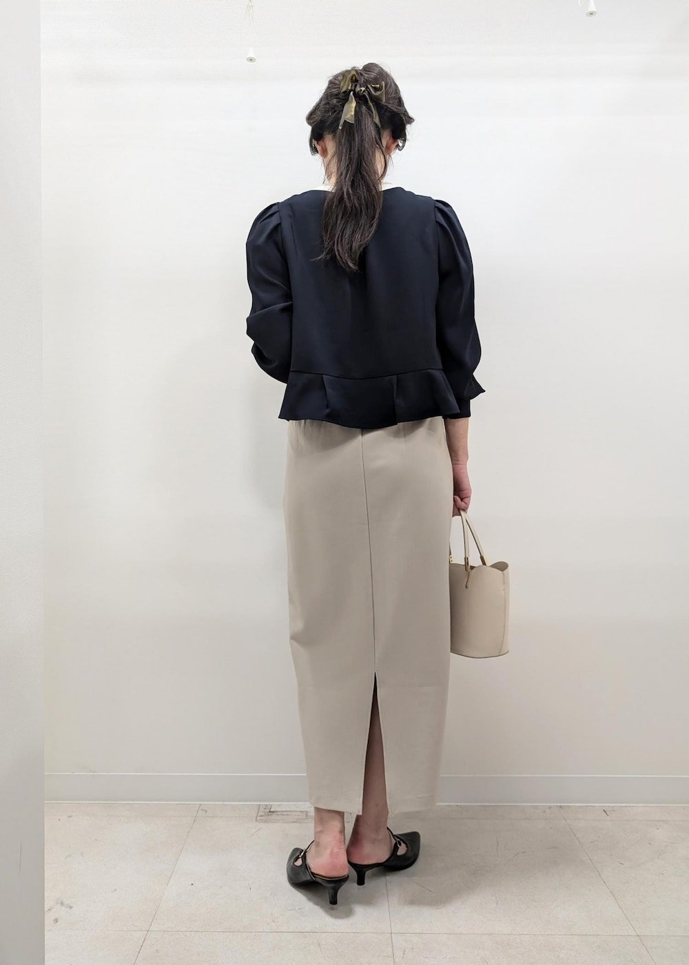 ベージュ系のスカート、ホワイト系のトートバッグ、ブラック系のパンプスを着用したレディースの秋コーディネートの4枚目の写真