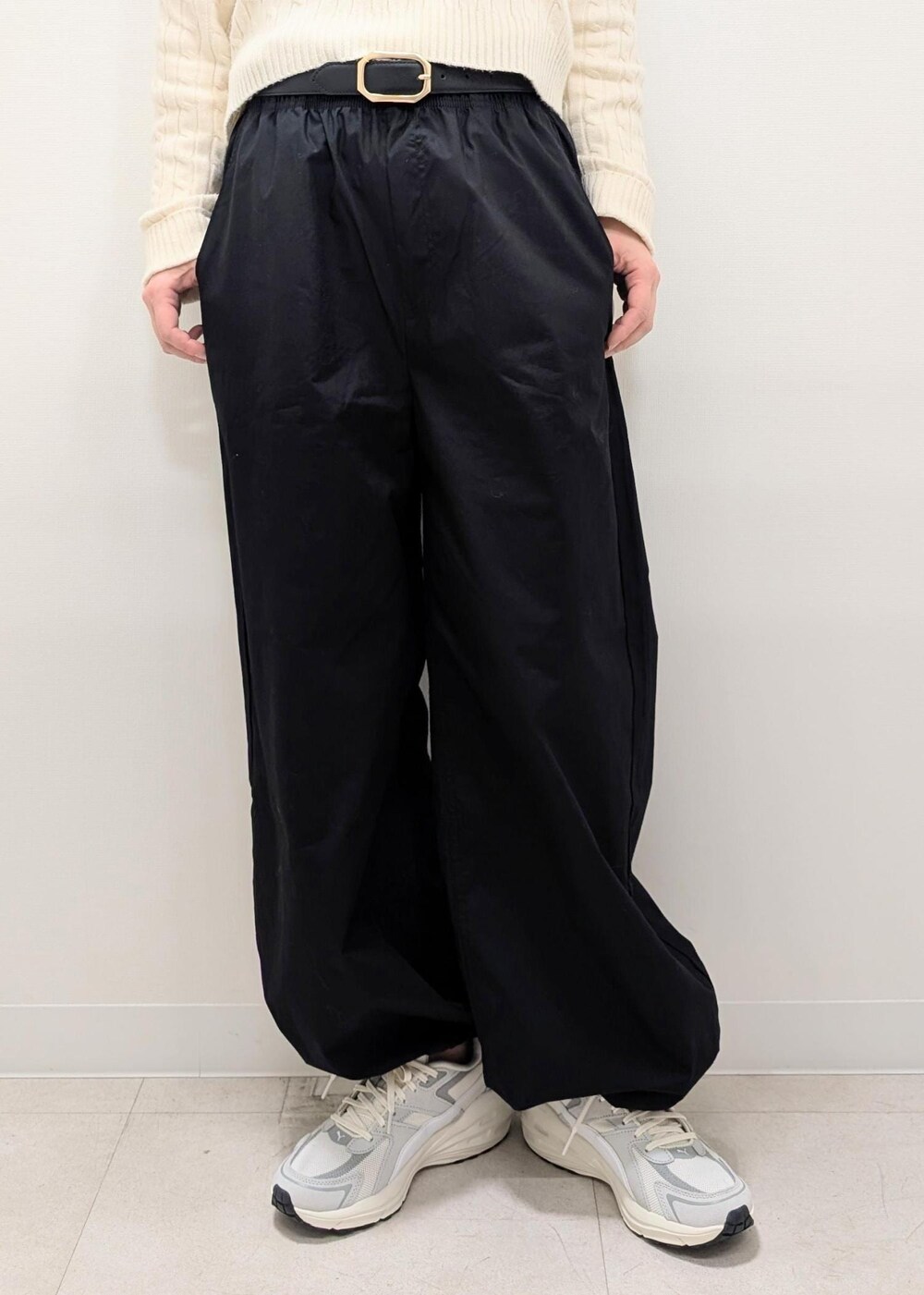 ブラック系のその他パンツ、ホワイト系のニット/セーター、グレー系のスニーカーを着用したレディースの春コーディネートの5枚目の写真