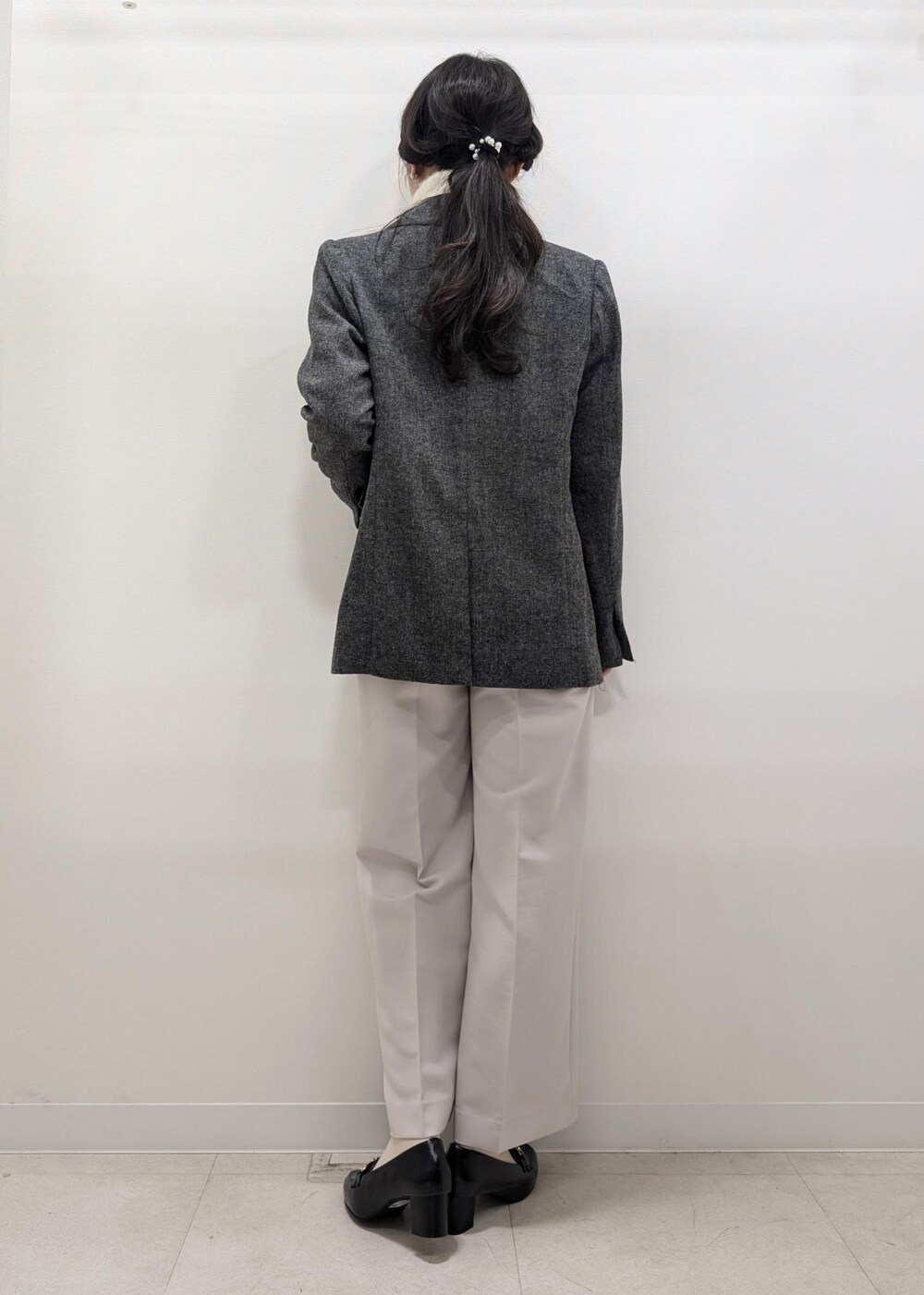 ホワイト系のニット/セーター、ブラック系のテーラードジャケット、ブラック系のショルダーバッグを着用したレディースの冬コーディネートの4枚目の写真