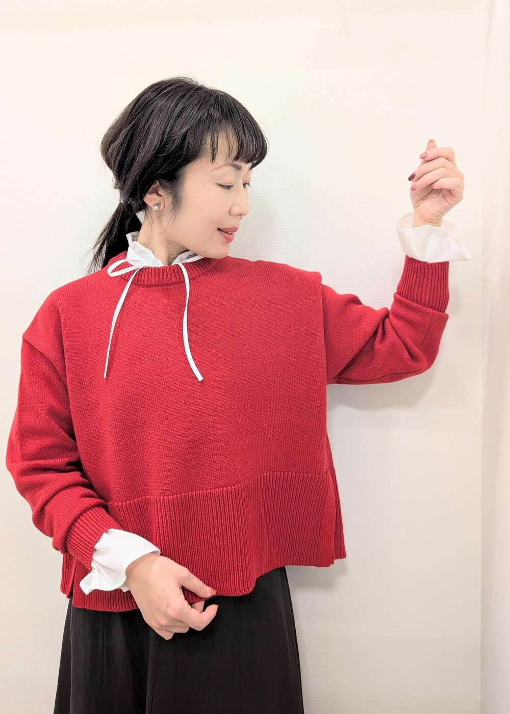 レッド系のニット/セーター、グレー系のスカート、ベージュ系のショルダーバッグを着用したレディースの秋コーディネートの5枚目の写真