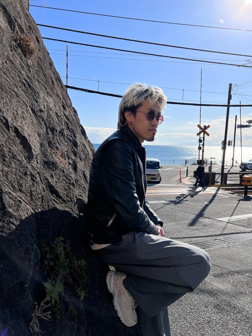 グレー系のチノパンツ、ベージュ系のスニーカー、ブラック系のムートンコートを着用したメンズの冬コーディネートの3枚目の写真