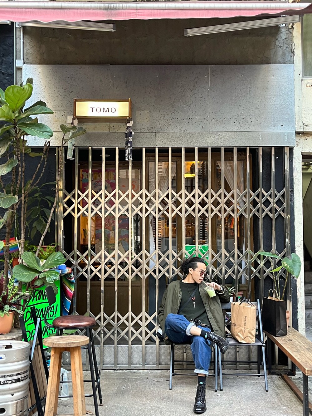 グリーン系のノーカラージャケット、グリーン系のニット/セーター、ブルー系のデニムパンツを着用したメンズの秋コーディネートの2枚目の写真