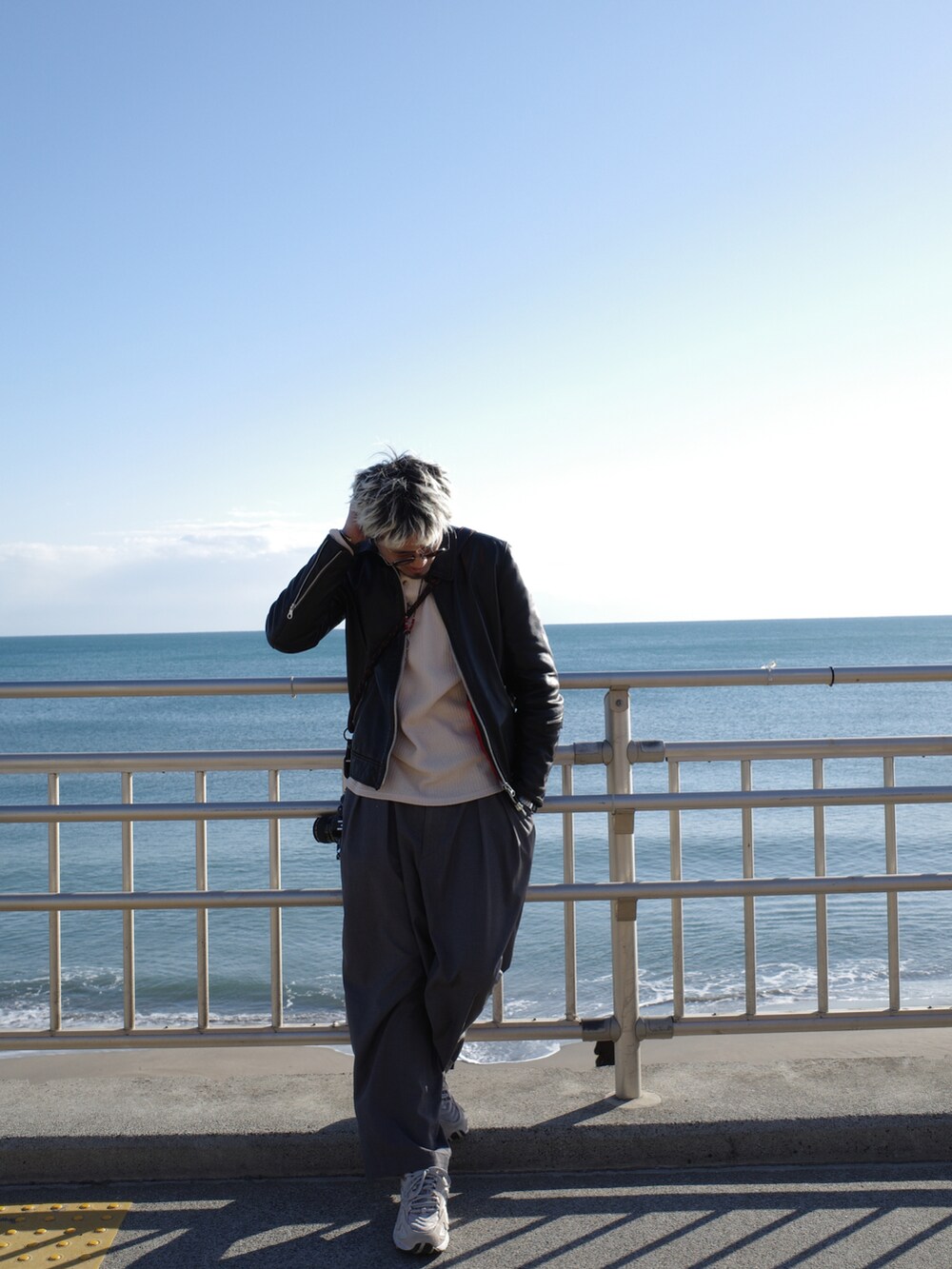 グレー系のチノパンツ、ベージュ系のスニーカー、ブラック系のムートンコートを着用したメンズの冬コーディネートの4枚目の写真