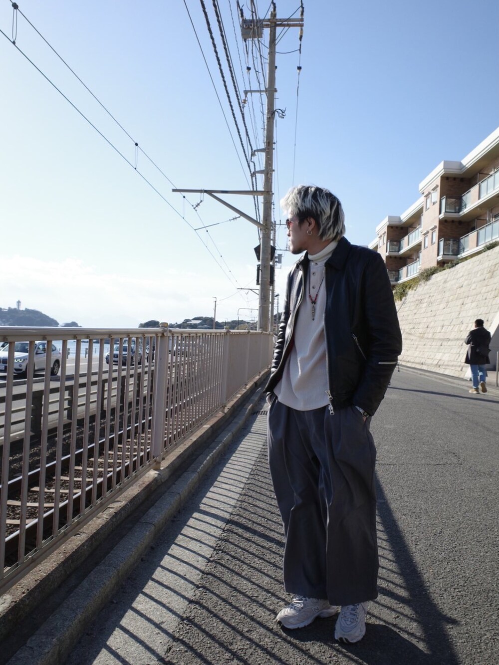 グレー系のチノパンツ、ベージュ系のスニーカー、ブラック系のムートンコートを着用したメンズの冬コーディネートの2枚目の写真