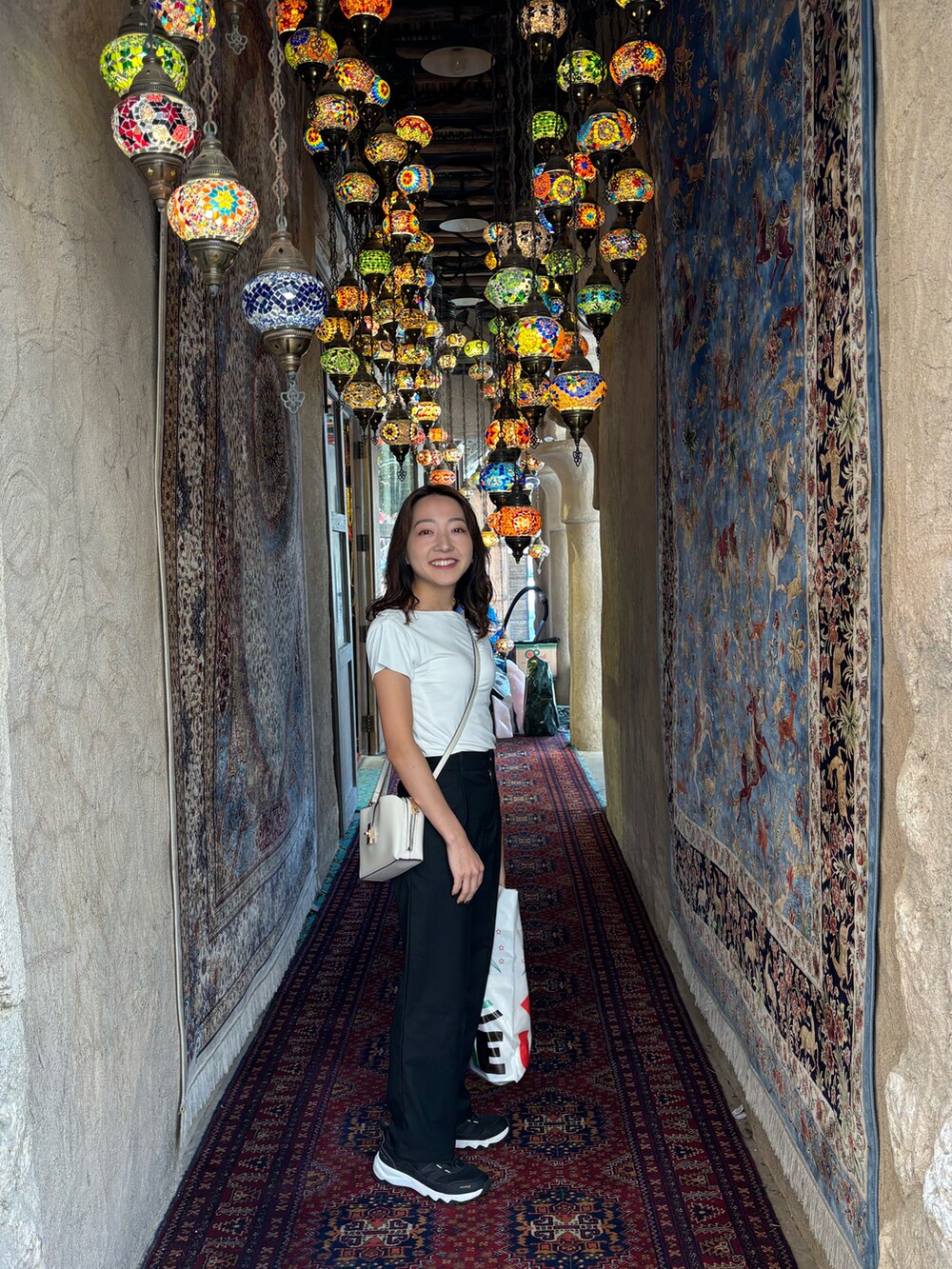 ホワイト系のショルダーバッグ、ブラック系のパンツを着用したレディースの春コーディネートの2枚目の写真