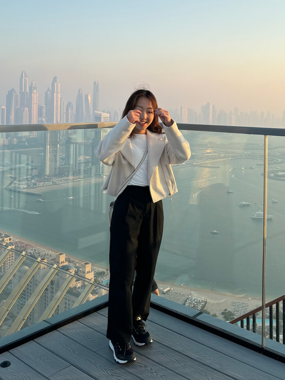 ホワイト系のショルダーバッグ、ブラック系のパンツを着用したレディースの春コーディネートの3枚目の写真