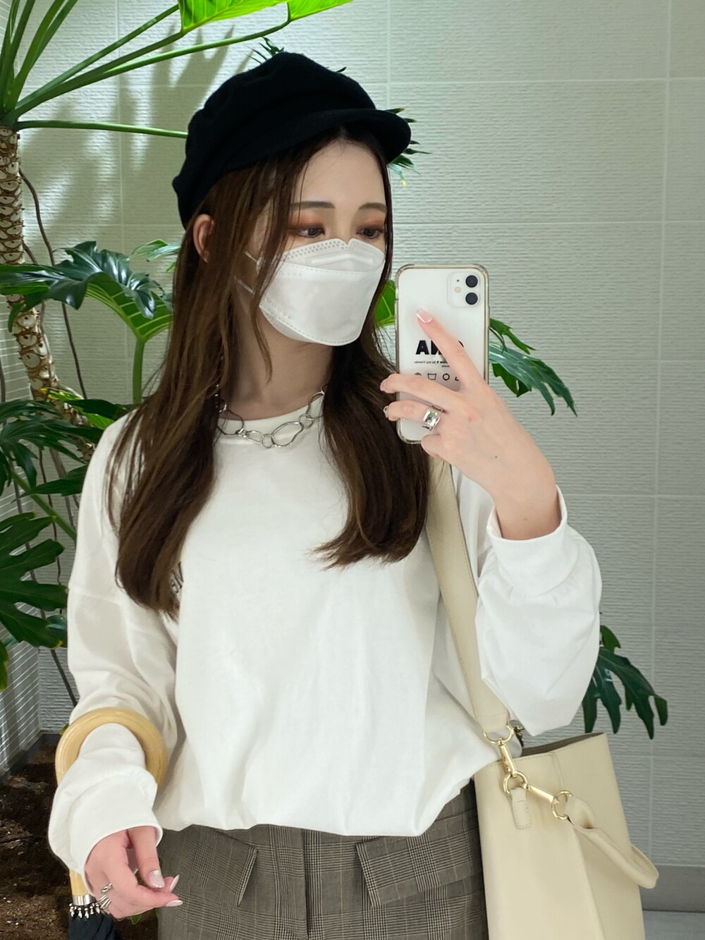 ベージュ系のスカート、ホワイト系のTシャツ/カットソー、ブラック系のブーツを着用したレディースの秋コーディネートの2枚目の写真