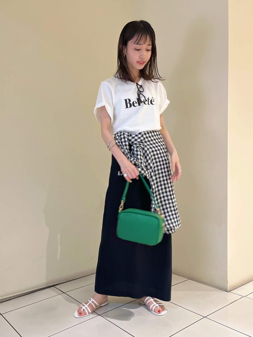 ブラック系のスカート、ホワイト系のTシャツ/カットソー、ホワイト系のサンダルを着用したレディースの夏コーディネートの2枚目の写真