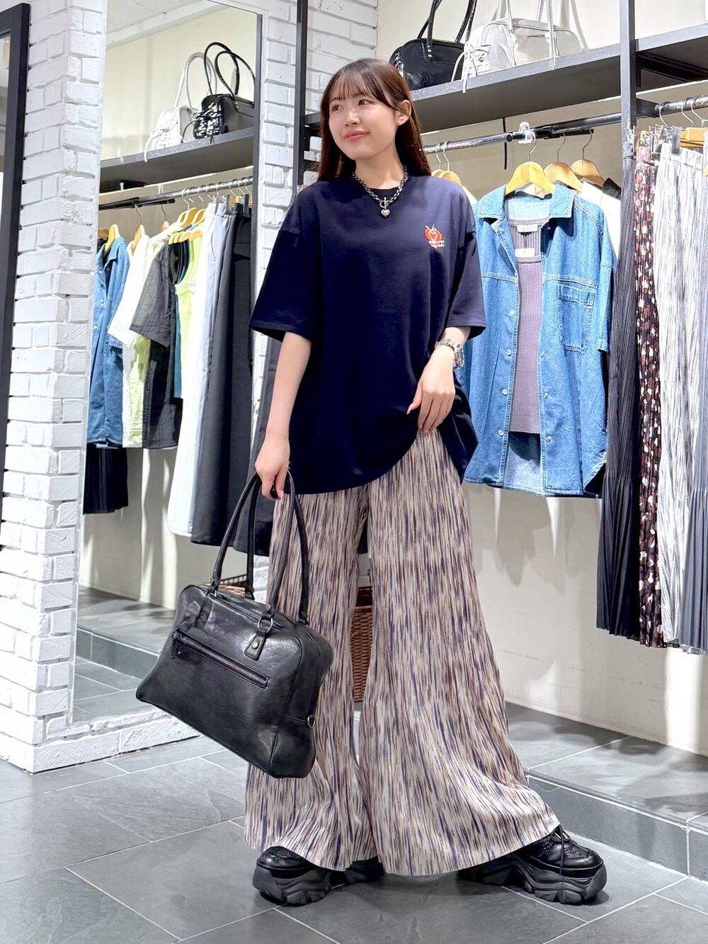 ブラック系のスニーカー、ブラック系のボストンバッグ、ブルー系のTシャツ/カットソーを着用したレディースの夏コーディネートの3枚目の写真