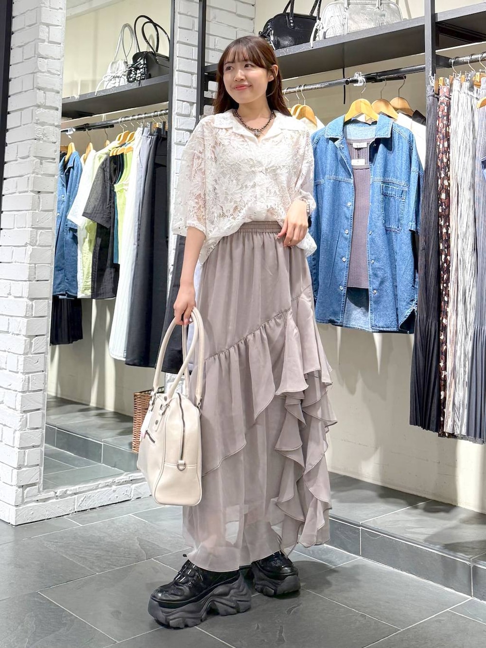 ブラック系のスニーカー、ホワイト系のボストンバッグ、グレー系のスカートを着用したレディースの夏コーディネートの3枚目の写真