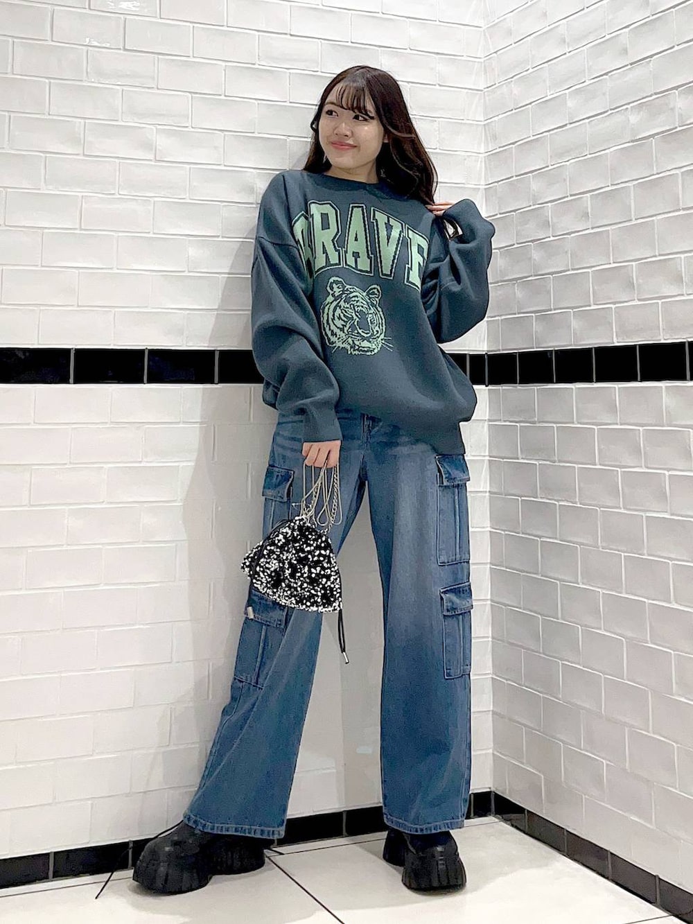 ブラック系のブーツ、シルバー系のショルダーバッグ、グリーン系のニット/セーターを着用したレディースの冬コーディネートの3枚目の写真