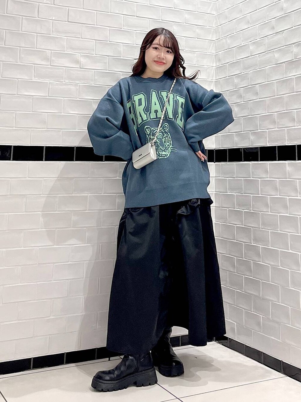 ブラック系のブーツ、シルバー系のショルダーバッグ、グリーン系のニット/セーターを着用したレディースの冬コーディネートの2枚目の写真