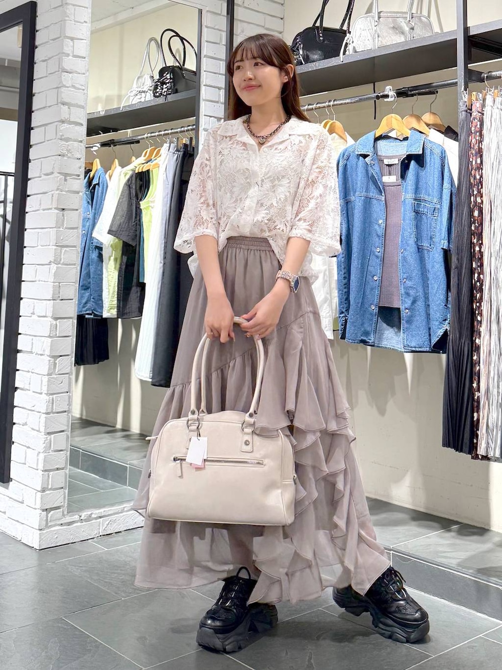 ブラック系のスニーカー、ホワイト系のボストンバッグ、グレー系のスカートを着用したレディースの夏コーディネートの4枚目の写真