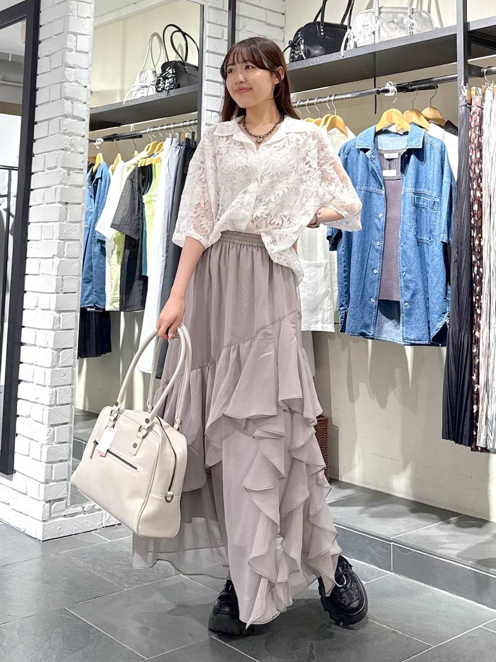 ブラック系のスニーカー、ホワイト系のボストンバッグ、グレー系のスカートを着用したレディースの夏コーディネートの2枚目の写真