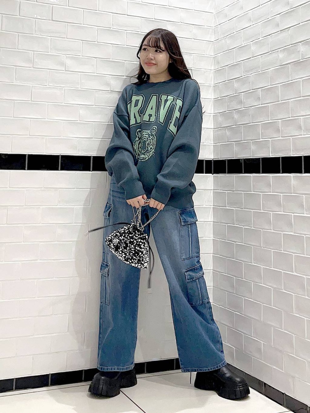 ブラック系のブーツ、シルバー系のショルダーバッグ、グリーン系のニット/セーターを着用したレディースの冬コーディネートの2枚目の写真