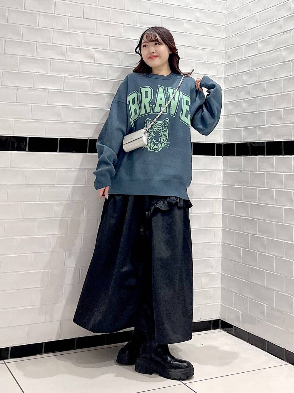 ブラック系のブーツ、シルバー系のショルダーバッグ、グリーン系のニット/セーターを着用したレディースの冬コーディネートの3枚目の写真