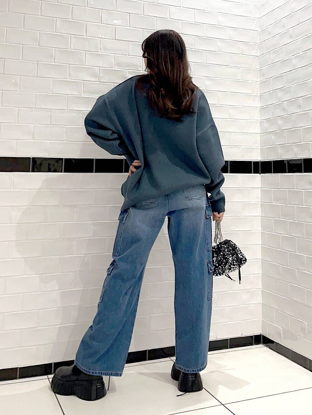 ブラック系のブーツ、シルバー系のショルダーバッグ、グリーン系のニット/セーターを着用したレディースの冬コーディネートの5枚目の写真