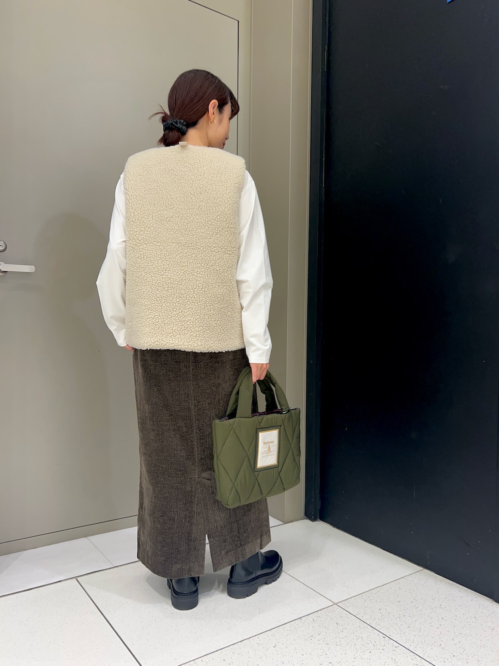 ホワイト系のベスト、ホワイト系のTシャツ/カットソー、ブラウン系のスカートを着用したレディースの秋コーディネートの5枚目の写真