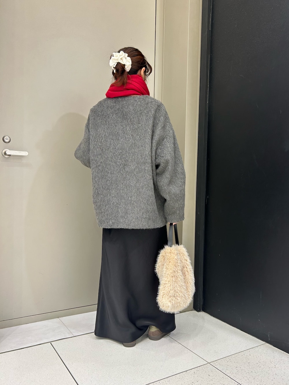 グレー系のノーカラージャケット、ホワイト系のハンドバッグ、レッド系のストール/ショールを着用したレディースの冬コーディネートの3枚目の写真