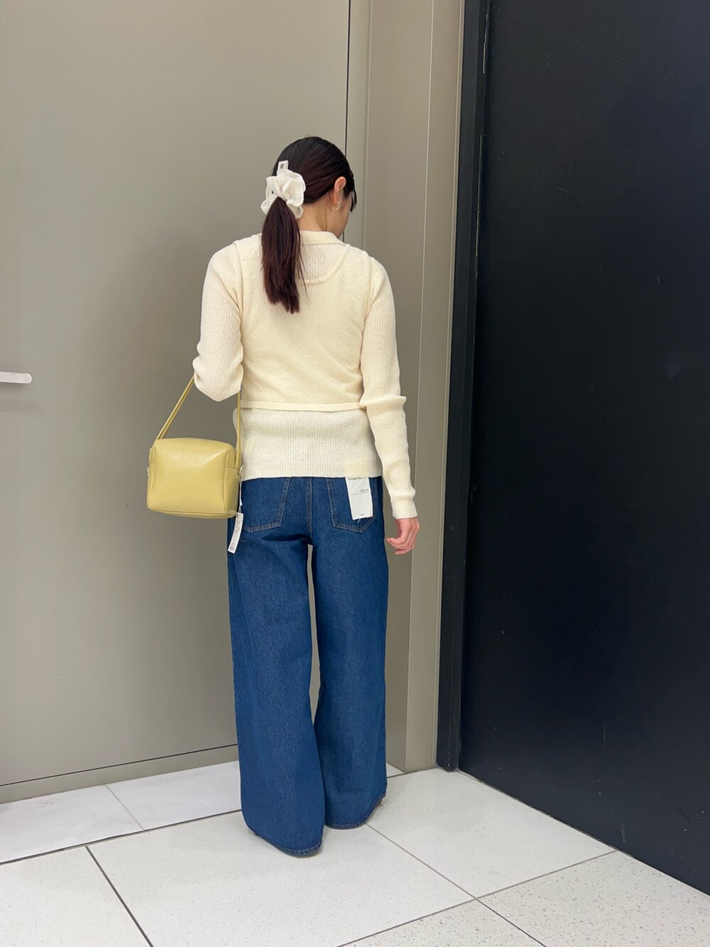 ホワイト系のニット/セーター、ブルー系のデニムパンツ、ベージュ系のショルダーバッグを着用したレディースの春コーディネートの3枚目の写真