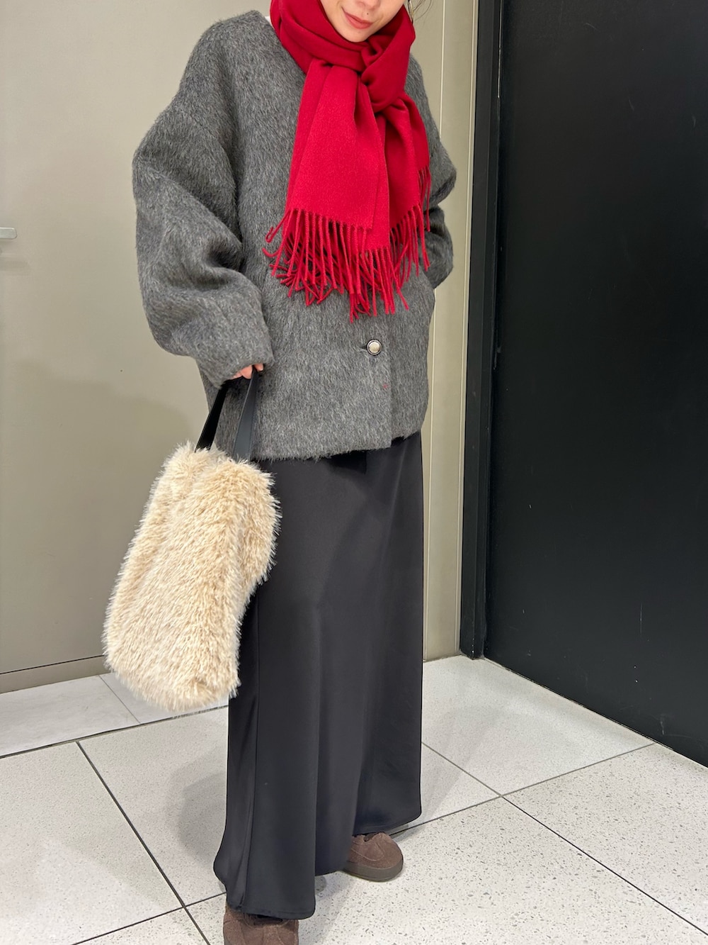 グレー系のノーカラージャケット、ホワイト系のハンドバッグ、レッド系のストール/ショールを着用したレディースの冬コーディネートの4枚目の写真