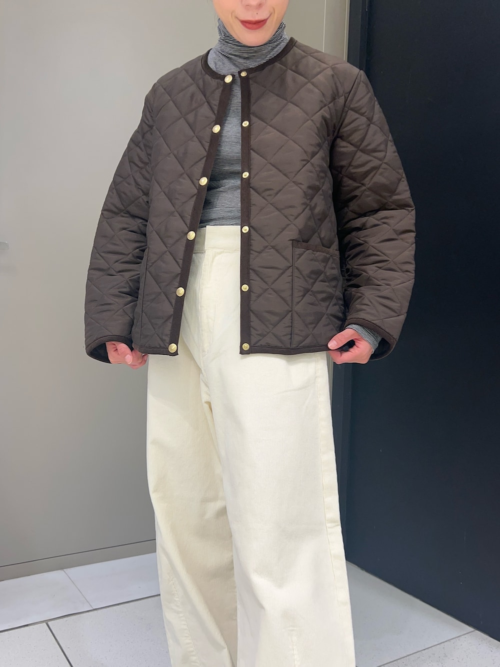 ブラウン系のノーカラーコート、ブラック系のTシャツ/カットソー、ホワイト系のその他パンツを着用したレディースの秋コーディネートの3枚目の写真