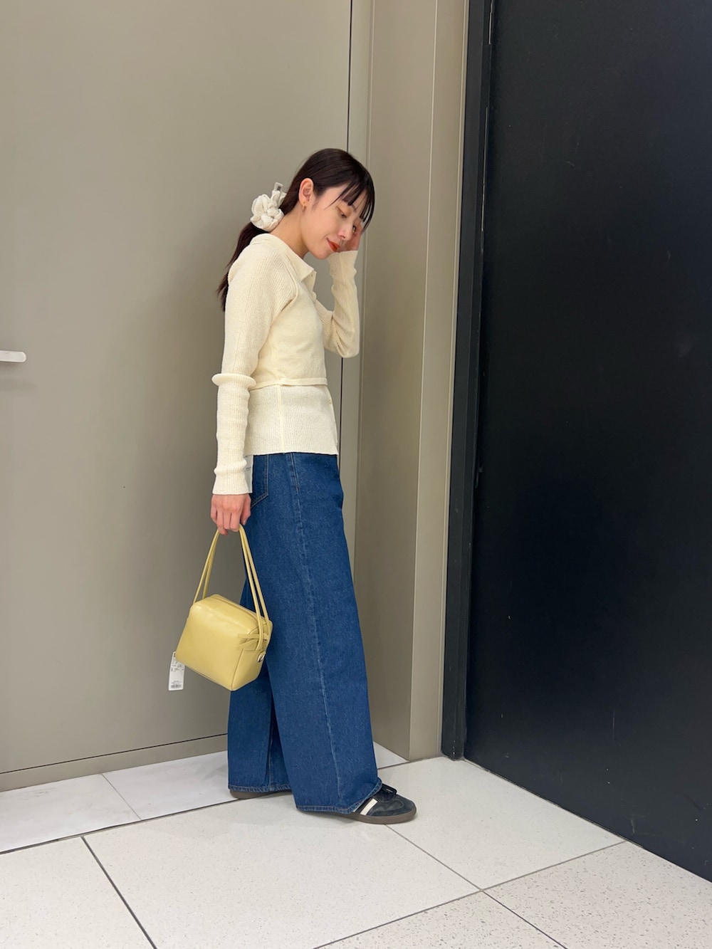 ホワイト系のニット/セーター、ブルー系のデニムパンツ、ベージュ系のショルダーバッグを着用したレディースの春コーディネートの2枚目の写真