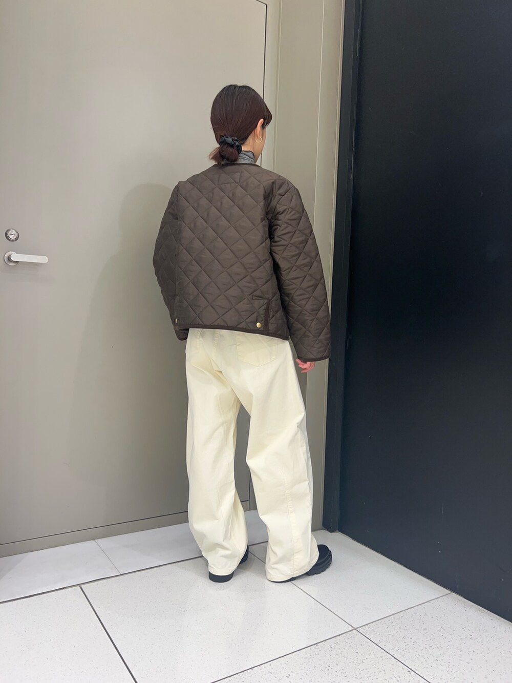 ブラウン系のノーカラーコート、ブラック系のTシャツ/カットソー、ホワイト系のその他パンツを着用したレディースの秋コーディネートの2枚目の写真