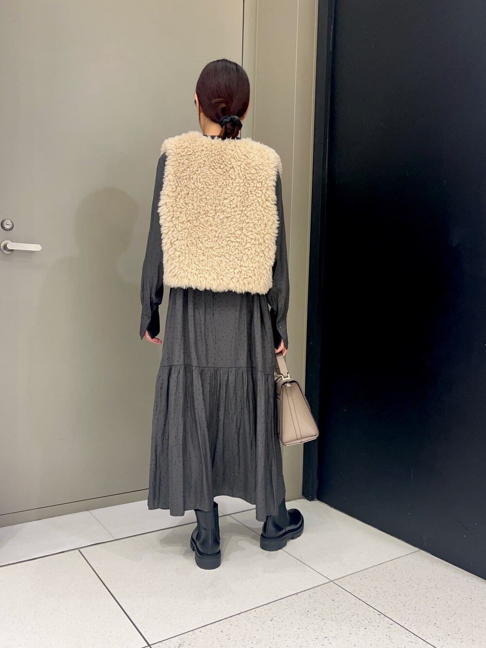 ベージュ系のその他アウター、グレー系のワンピース、グレー系のハンドバッグを着用したレディースの秋コーディネートの2枚目の写真