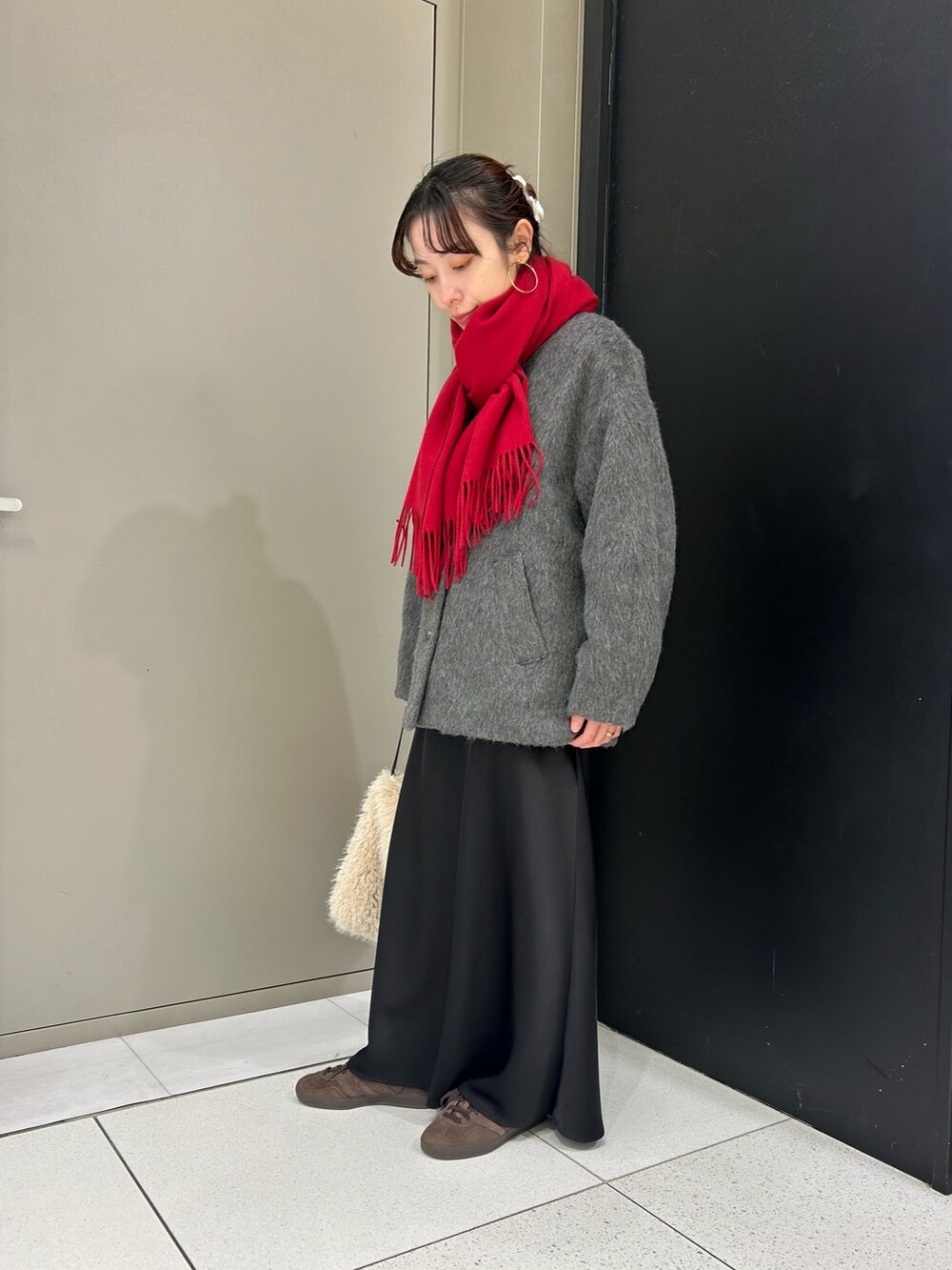 グレー系のノーカラージャケット、ホワイト系のハンドバッグ、レッド系のストール/ショールを着用したレディースの冬コーディネートの2枚目の写真