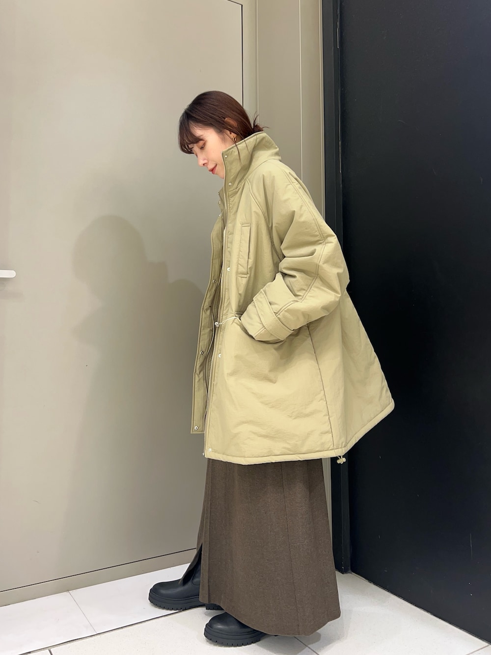 ベージュ系のニット/セーター、ブルー系のダウンジャケット/コート、ブラウン系のスカートを着用したレディースの秋コーディネートの3枚目の写真
