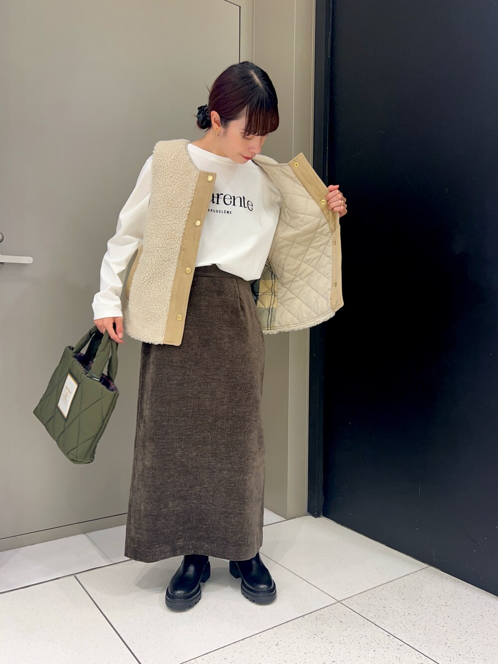 ホワイト系のベスト、ホワイト系のTシャツ/カットソー、ブラウン系のスカートを着用したレディースの秋コーディネートの3枚目の写真