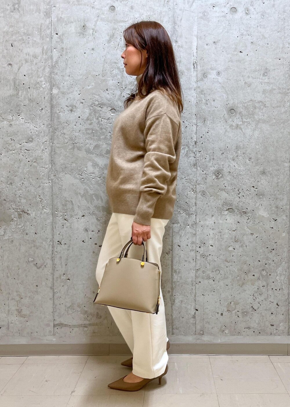 ベージュ系のパンプス、ベージュ系のハンドバッグ、ホワイト系のその他パンツを着用したレディースの冬コーディネートの2枚目の写真